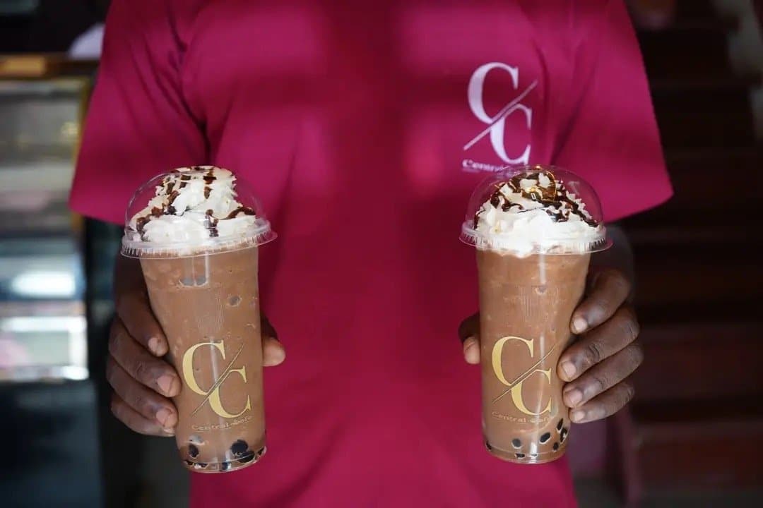 Two chocolate boba drinks held out in front of a burgundy Central Cafè shirt