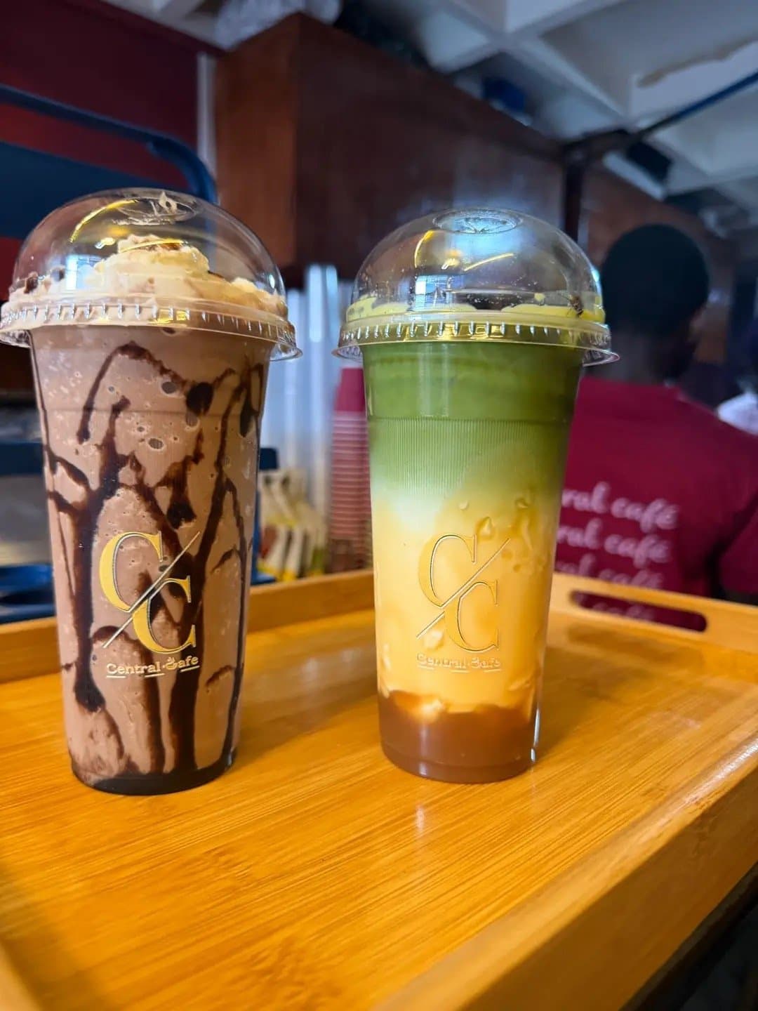 A chocolate drink and a layered mango matcha on a tray