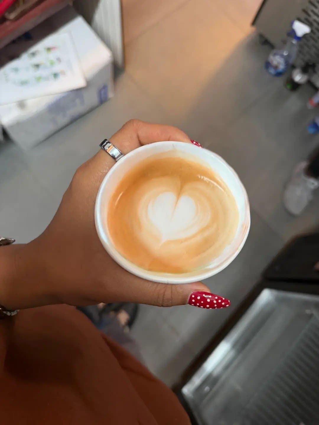 A latte with a heart held in one hand