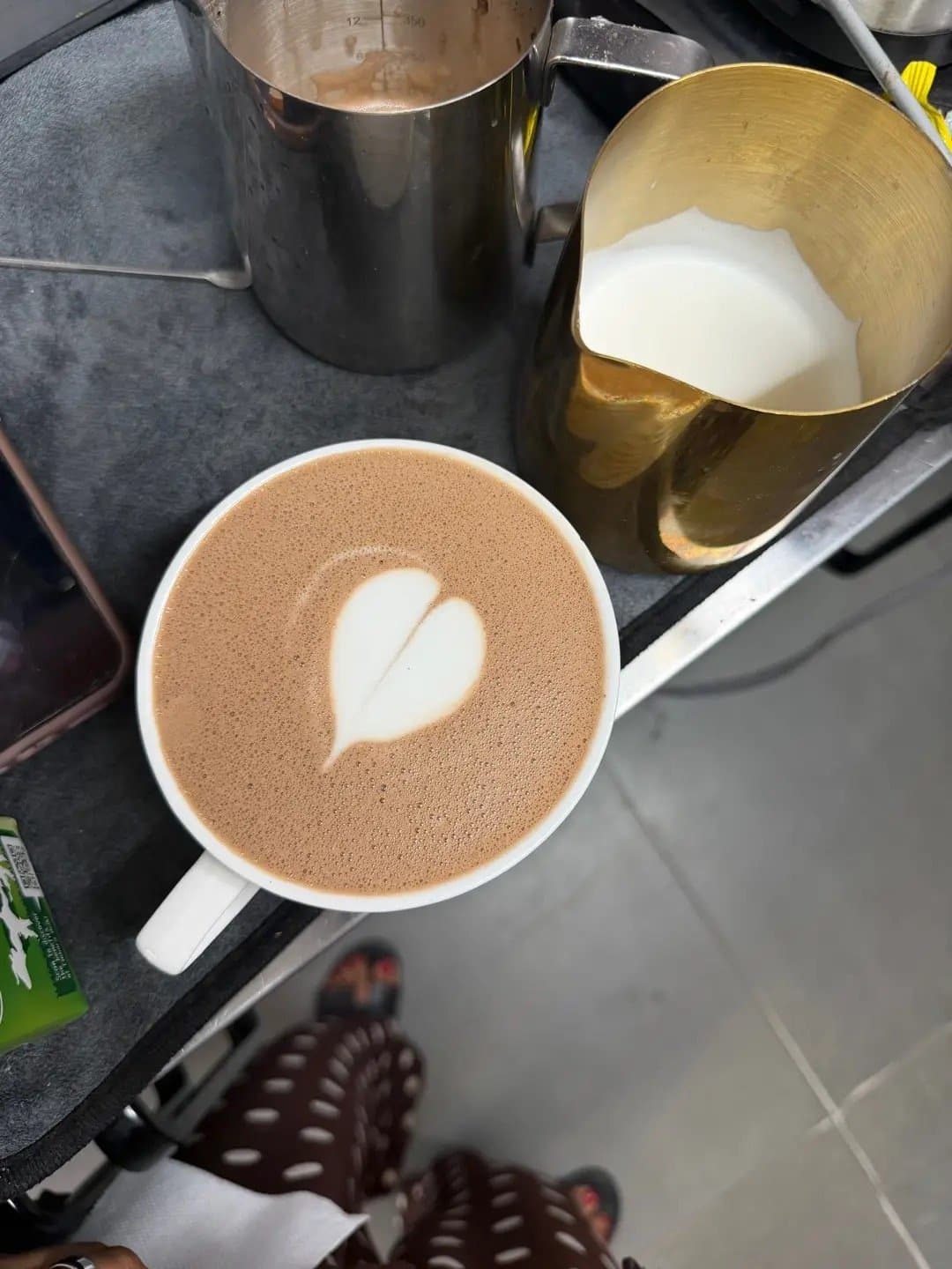 A heart latte beside a steaming jug