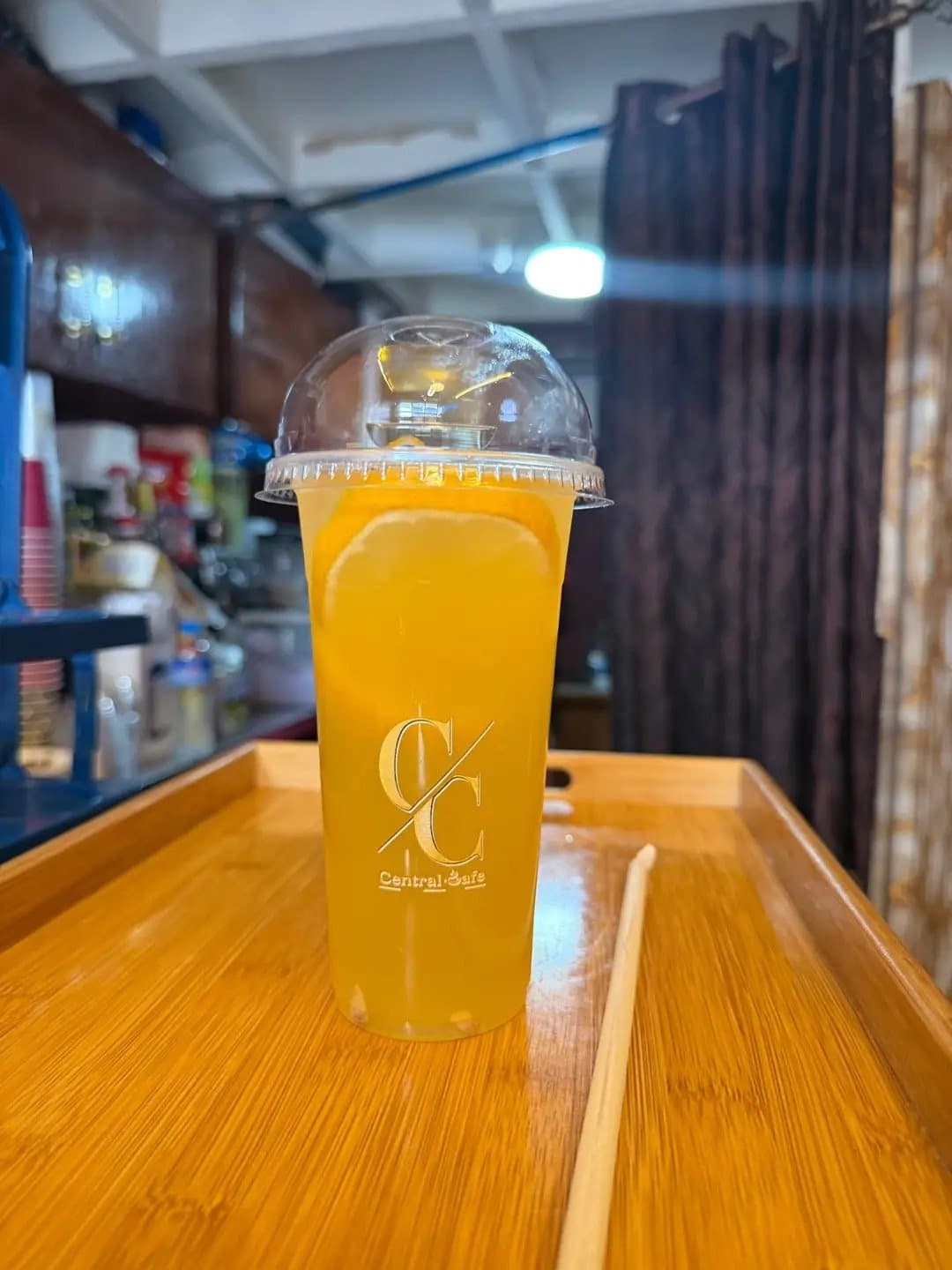 A bright orange cold drink in a Central Cafè cup on a tray