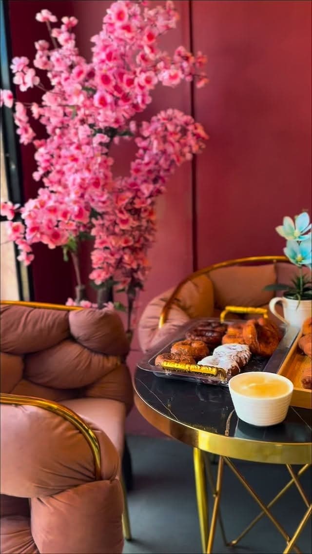 A corner of Central Cafè with cherry blossom, tan leather seating and pastries on a gold-rimmed marble table