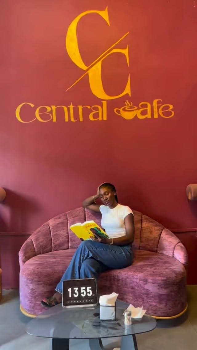A customer reading on the mauve velvet sofa beneath the Central Cafè sign